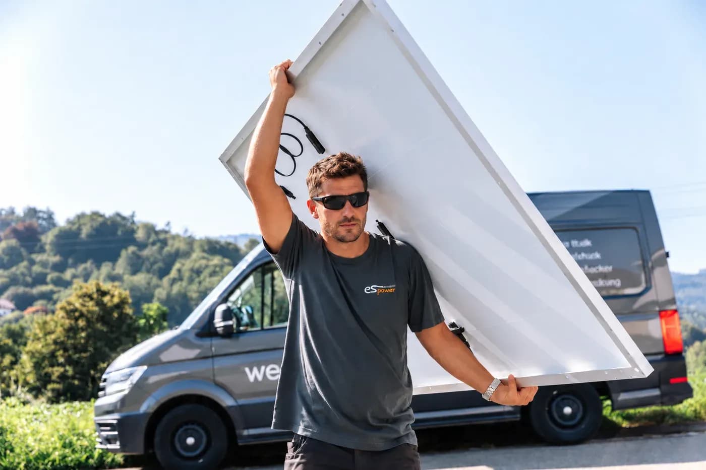 Monteur mit Solarmodul vor dem Servicewagen