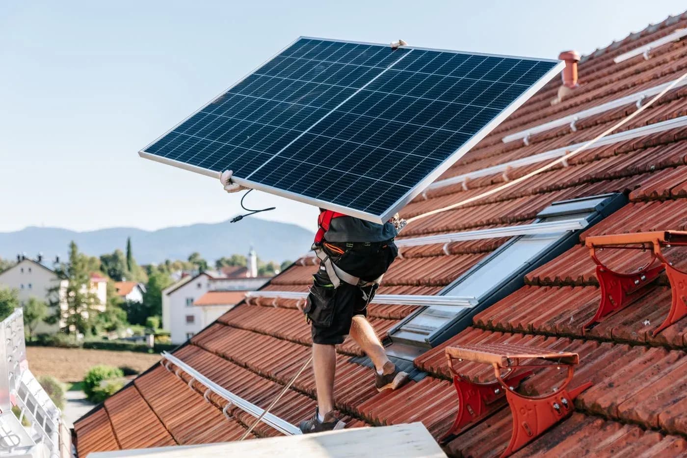 Handwerker tragen ein Solarmodul über das Dach