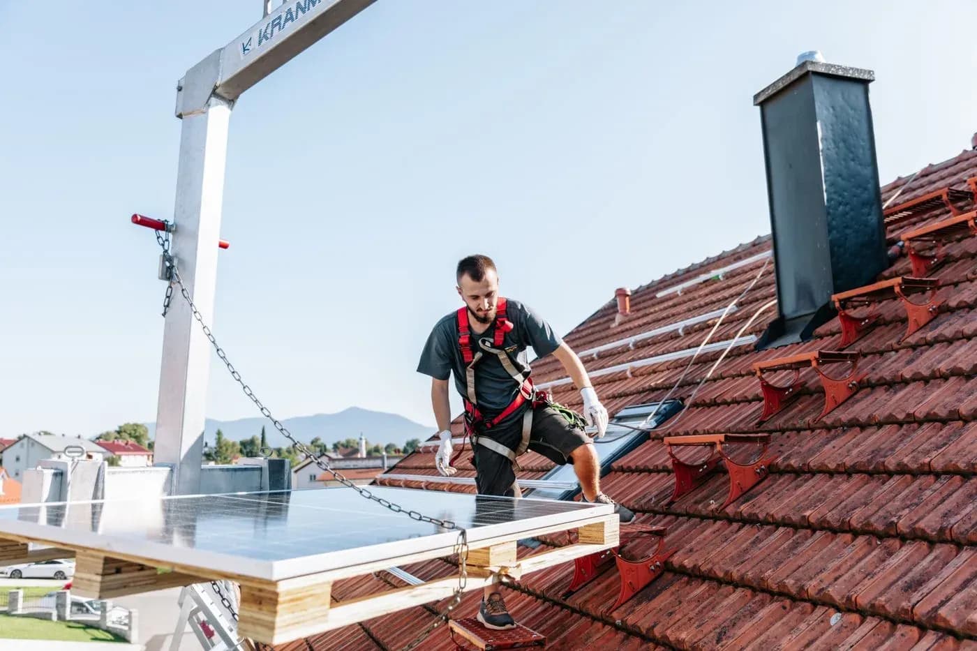 Kran hebt ein Solarmodul zum Dach