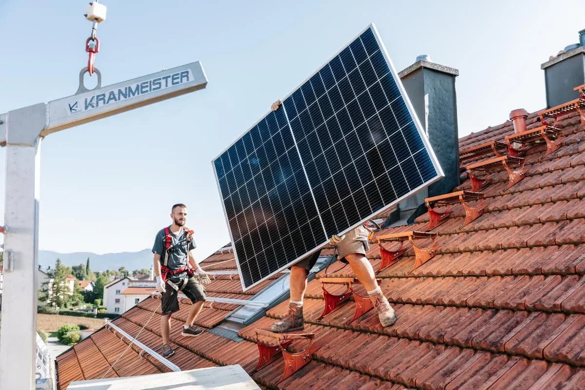 Solarmodule werden per Kran auf ein Dach gehoben