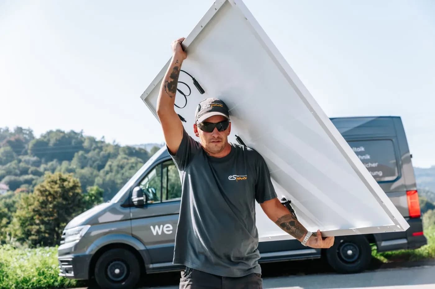 Monteur mit Solarmodul vor dem Servicewagen