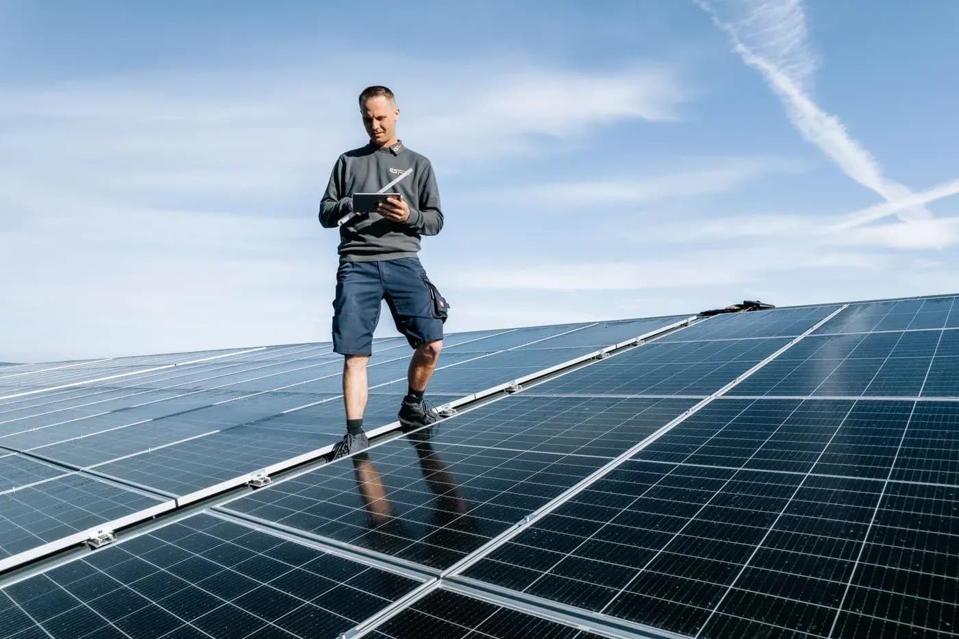Techniker mit Tablet auf dem PV-Dach